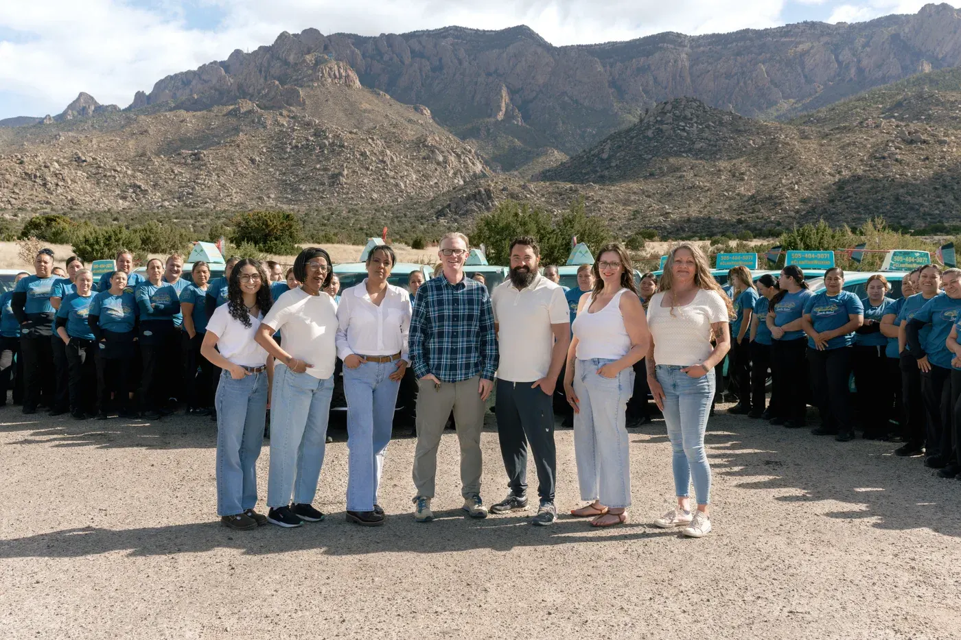 The full Sandia Green Clean team and teal fleet in front of the Sandia mountains