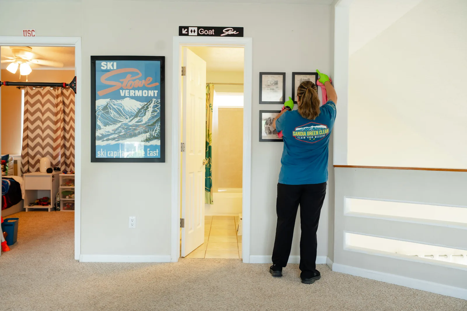 Sandia Green Clean team member wiping down hallway walls and door frames