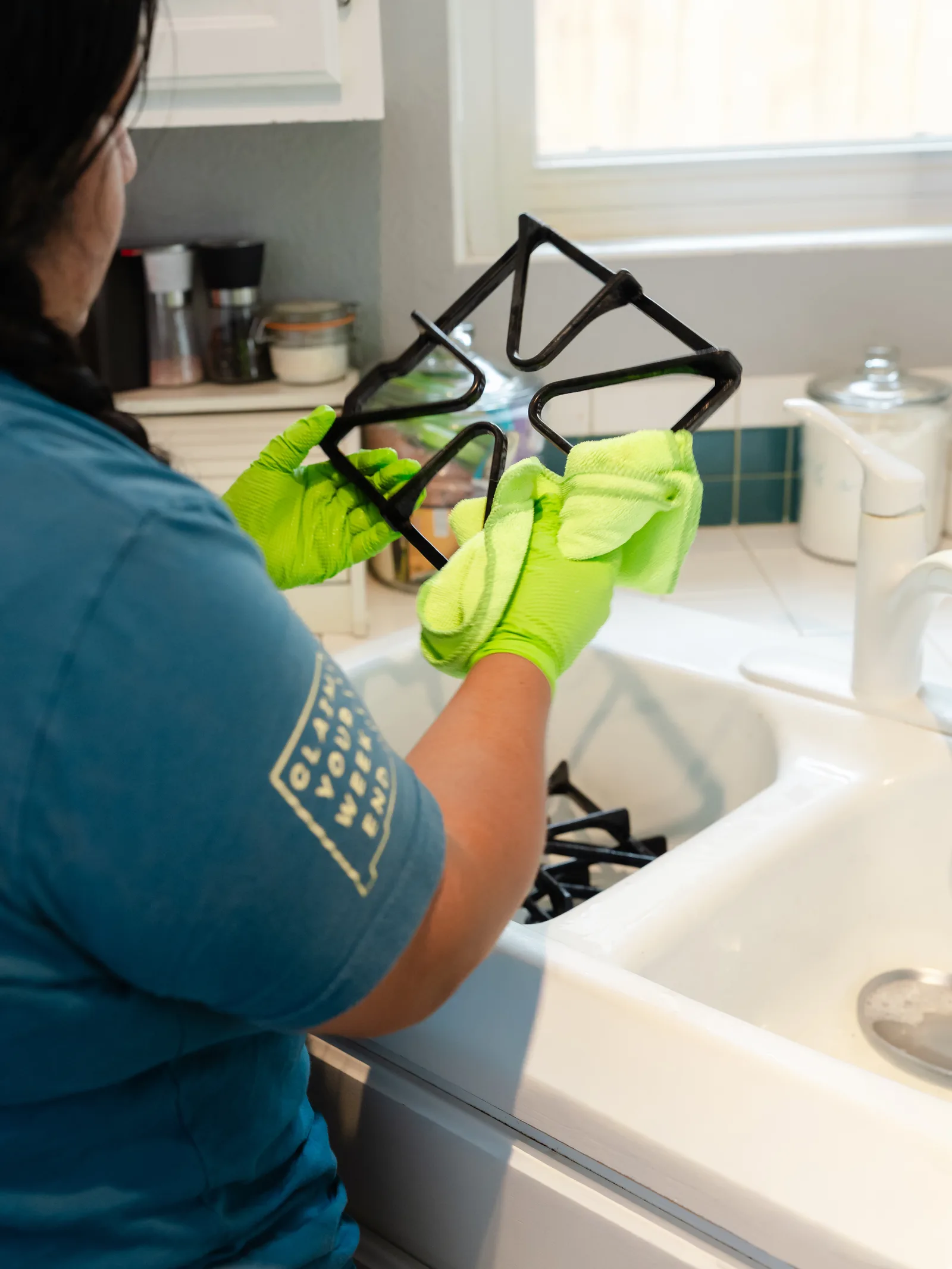 Sandia Green Clean team member washing stove grates in the sink